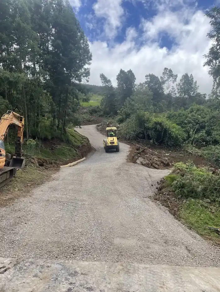 Compacted gravel access road curving uphill through green Upcountry Maui terrain