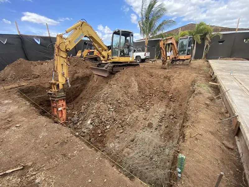 Two excavators cutting a rectangular swimming pool excavation behind silt fencing