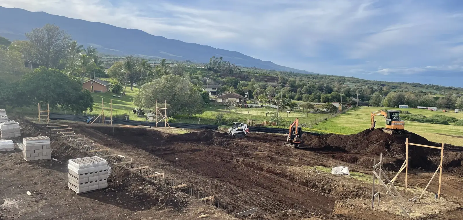 House pad cut and benched into an Upcountry Maui lot, with the West Maui mountains behind